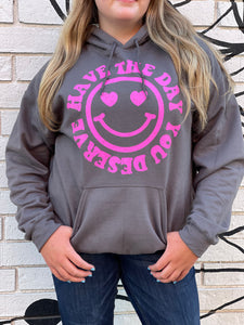 HAVE THE DAY YOU DESERVE SMILEY FACE: charcoal gray hoodie with hot pink graphic